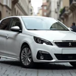 Vue trois-quarts avant de la Peugeot 308 Phase 3 garée sur un pavé urbain européen, illustrant ses dimensions extérieures complètes